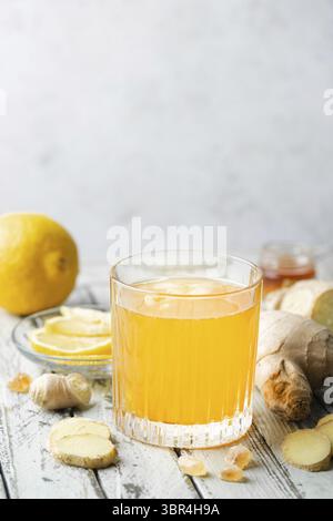 Gelbes Getränk mit Ingwer, Zitrone und Eis im Glas, erfrischende hausgemachte Ingwer-Limonade oder Ale auf weißem Hintergrund Stockfoto