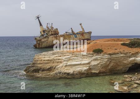 Paphos, Zypern - 25. Juni 2025: Blick auf das verwitterte, rostgestreute Schiffswrack Edro III, das prekär auf den zerklüfteten, sonnenverwöhnten Klippen thront, ein krasser Kontrast zum türkisfarbenen Meer. Stockfoto