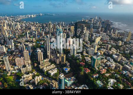 Aus der Vogelperspektive auf einen Betondschungel, in dem Türme die Skyline mit dem Arabischen Meer als Kulisse durchstechen, Marine Drive sichtbar in der Ferne, Mumbai, Maharashtra, Indien. Stockfoto