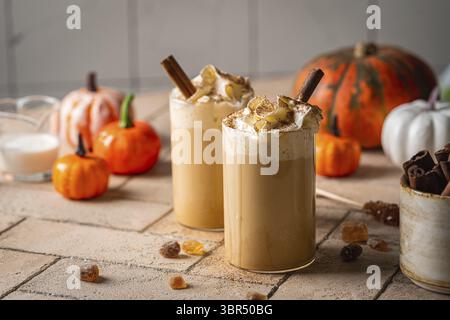 Herbstlicher Kürbis-Latte mit Schlagsahne und Zimt auf hellem Hintergrund Stockfoto