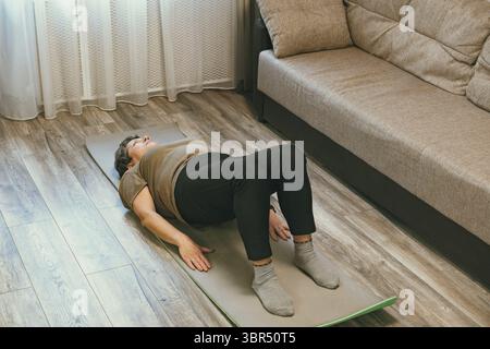 Sport Im Reifen Alter. Glückliche ältere Frau macht Stretching-Übungen zu Hause, beobachten Online-Tutorials Stockfoto