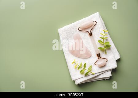 Jade-Gesichtsrollen und Gua-Sha-Steine für Schönheits-Gesichtsmassagetherapie, Artikel für Hausbehandlung mit Hautpflege Anti-Aging-Tools auf grünem Hintergrund, Stockfoto