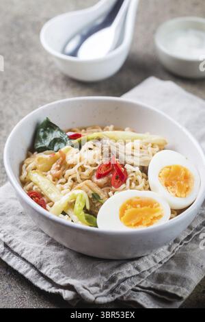 Japanische Ramen-Nudeln mit Huhn, Shiitake-Pilzen und Ei in einer weißen Schüssel Stockfoto