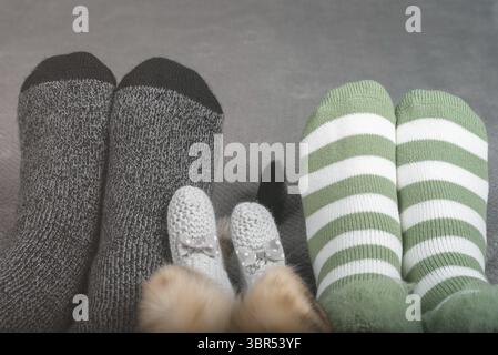 Beine einer Frau, eines Mannes und einer Katze in Socken in einem Wohnraum auf einer warmen Decke Stockfoto