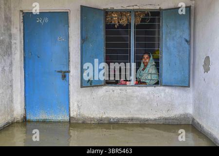 16. Juli 2020, Bogura, Bangladesch: Eine Frau sitzt in ihrem überfluteten Haus in Bogura. Ein Drittel von Bangladesch ist unter Wasser, nachdem heftige Regenfälle das Land getroffen haben. Mindestens 1,5 Millionen Menschen sind betroffen, Häuser und Straßen in Dörfern sind überflutet. Beamte des Flood Forecasting and Warning Centre (FFWC) berichteten, dass die Hochwassersituation in 15 nördlichen und zentralen Distrikten auf den Anstieg der Wasserstände der wichtigsten Flüsse, einschließlich Brahmaputra, Jamuna, Padma, Teesta und Dharla, zurückzuführen ist. (Credit Image: © Zabed Hasnain Chowdhury/SOPA Images via ZUMA Wire) Stockfoto