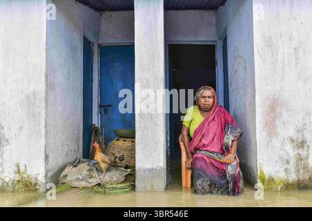 16. Juli 2020, Bogura, Bangladesch: Eine Frau sitzt vor ihrem überfluteten Haus in Bogura. Ein Drittel von Bangladesch ist unter Wasser, nachdem heftige Regenfälle das Land getroffen haben. Mindestens 1,5 Millionen Menschen sind betroffen, Häuser und Straßen in Dörfern sind überflutet. Beamte des Flood Forecasting and Warning Centre (FFWC) berichteten, dass die Hochwassersituation in 15 nördlichen und zentralen Distrikten auf den Anstieg der Wasserstände der wichtigsten Flüsse, einschließlich Brahmaputra, Jamuna, Padma, Teesta und Dharla, zurückzuführen ist. (Credit Image: © Zabed Hasnain Chowdhury/SOPA Images via ZUMA Wire) Stockfoto