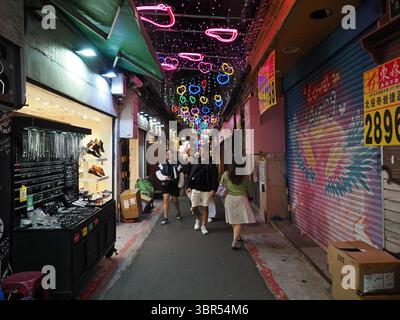 Taipei, Taiwan - 7. November 2024 - in der Raohe Street Night Mar spazieren die Menschen entlang einer Gasse, die mit einem Baldachin aus farbenfrohen Neonröhren geschmückt ist Stockfoto