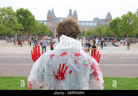 18. Juli 2020, Amsterdam, Niederlande: Man beobachtet einen Aktivisten der Tieraufstände während einer Protestaktion unter dem Motto Blut an den Händen am Museumplein während der Coronavirus-Pandemie am 18. Juli 2020 in Amsterdam, Niederlande. Die Animal Rebellion Netherlands Movement fordert die Regierung auf, einen Übergang zu einem pflanzlichen Lebensmittelsystem zu führen, um die Klimakrise zu lösen. (Kreditbild: © Paulo Amorim/VW Pics via ZUMA Wire) Stockfoto