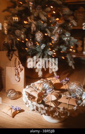 Präsentiert eine Sammlung von gewickelten Geschenken und glitzernden Ornamenten unter einem wunderschön verzierten Weihnachtsbaum. Das warme Ambiente bedeutet ein festliches Ambiente Stockfoto