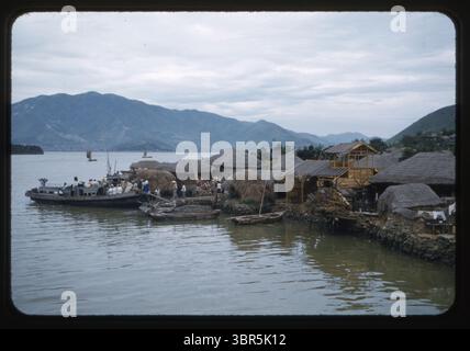 Ein traditionelles koreanisches Fischerdorf an der Küste zwischen Chinhae (Jinhae) und Masan in der südkoreanischen Provinz Gyeongsang, das im August 1956 eingenommen wurde. Häuser mit Strohdach, Fischerboote und Anwohner spiegeln das maritime Leben der Region nach dem Krieg wider. Dieses Foto wurde von Chief Petty Officer Wilfred K.C. Park, einem koreanischen Amerikaner, der in der US Navy diente, aufgenommen, der in den 1950er Jahren Leben und Militäroperationen in ganz Korea und Japan dokumentierte Stockfoto