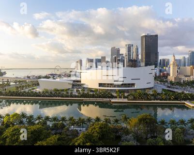Die geschwungene Architektur des Adrienne Arsht Centers spiegelt sich aus der Vogelperspektive im ruhigen Wasser wider, vor Miamis majestätischer Skyline im goldenen Licht, Miami, Florida, USA. Stockfoto