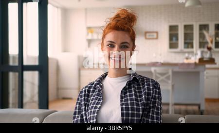 Lächelnde positive zufriedene kaukasische Frau fröhlich weiblich sorglos Mädchen zu Hause Couch entspannend Blick auf die Kamera im Wohnzimmer genießen Stockfoto
