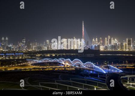 Dubai, Vereinigte Arabische Emirate - 16. Juni 2025: Aus der Vogelperspektive auf die beleuchtete Skyline von Dubai, mit dem Burj Khalifa und den eleganten Linien der Meydan Bridge bei Nacht. Stockfoto