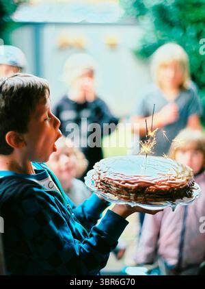 Boy bläst Kerzen auf Geburtstagskuchen Stockfoto