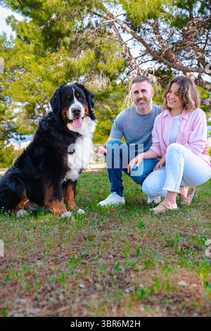 Kaukasisches Paar mit Hund, der draußen posiert und während des Urlaubs am Strand lächelt Stockfoto