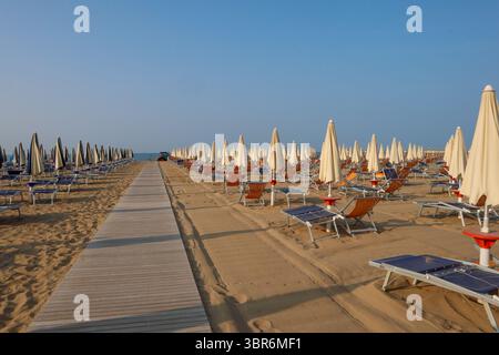 Leere Sonnenliegen und Sonnenschirme an einem ruhigen Strand am frühen Morgen Stockfoto