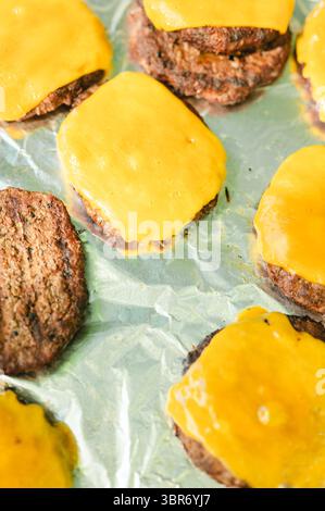 Ober-Sicht von Käseeburgern mit geschmolzenem Käse auf Folienoberfläche Stockfoto