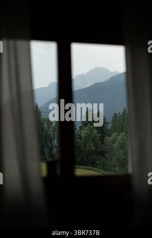 Ein stimmungsvoller Blick auf die Berge von einem ruhigen Cortina-Fenster umrahmt den perfekten alpinen Tagtraum. Stockfoto