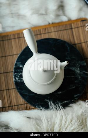 Minimalistische weiße japanische Kyusu-Teekanne auf Marmortablett und Bambusmatte Stockfoto