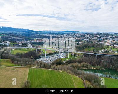 Aus der Vogelperspektive auf die Brücke Pont de la Poya, die über die üppige grüne Landschaft hinausragt, ein modernes Wunder vor der Kulisse der fernen Berge, Freiburg, Schweiz. Stockfoto