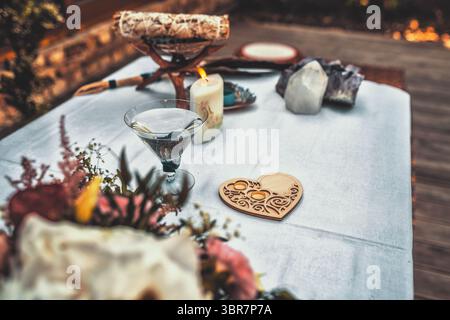 Baum mit Hochzeitsringen. Wunderschön gestalteter spiritueller Tisch mit Kerze, Kristallen und atemberaubendem Blumendekor. Natürliche Hochzeit. Stockfoto