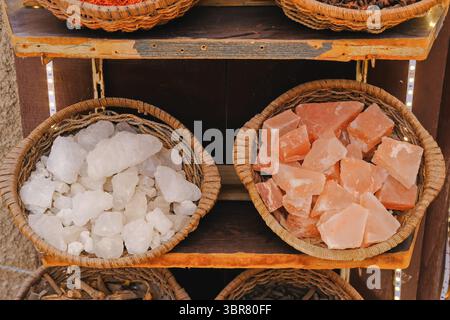 Körbe mit rohen Himalaya-rosa und weißen Steinsalzkristallen auf Regalen auf dem traditionellen Markt. Natürliche Mineralprodukte zum Verkauf im nahöstlichen Souk Stockfoto