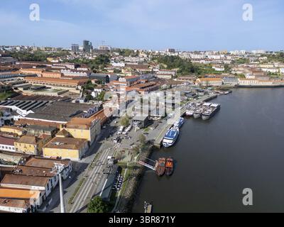 Blick aus der Vogelperspektive auf den Fluss Douro, der neben den Terrakottadächern von Vila Nova de Gaia und Industriegebäuden schimmert, Porto, Porto District, Portugal. Stockfoto