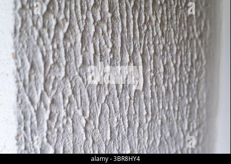 Nahaufnahme, Hintergrundstruktur einer beige-weißen Fassadenwand eines Hauses aus dekorativem Putz. Abstrakte Fläche Stockfoto