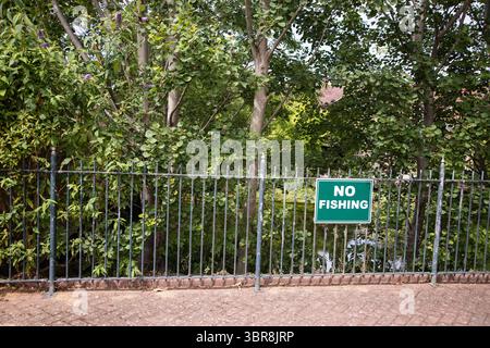 Grünes „No Fishing“-Schild auf Metallgeländern im Enfield Island Village, mit grünem Grün und dem Fluss Lea im Hintergrund – Highlight Stockfoto