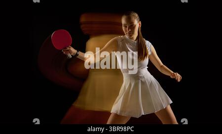Fokussierte Tischtennisspielerin mit verschwommener Bewegung hinten auf schwarzem Hintergrund Stockfoto