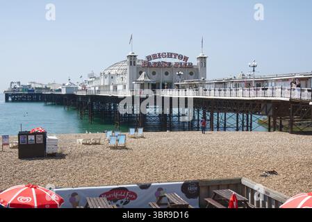 Brighton Palace Pier und Shingle Beach in Brighton in East Sussex, England. Mit Leuten und Strandcafé. Stockfoto