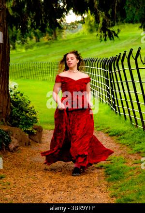 Eine Frau in rotem Kleid läuft auf einem Weg in einem Park. Stockfoto