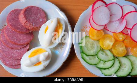 Köstliches Frühstück mit Aufschnitt, gekochten Eiern und lebendigem Gemüse. Stockfoto