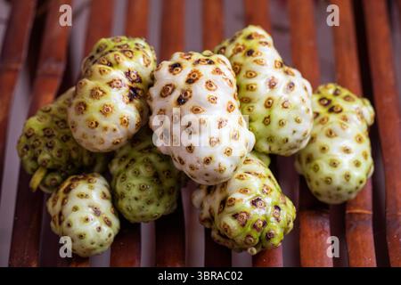 Exotische Noni-Früchte, die wunderschön auf einer rustikalen Holzoberfläche angeordnet sind, sorgen für einen ansprechenden Look Stockfoto