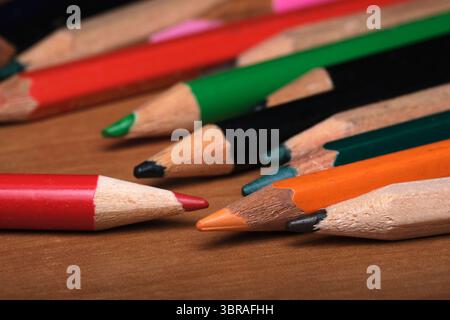 Farbenfrohe Bleistifte liegen auf einem Holztisch und sind bereit für künstlerische Ausdrucksmöglichkeiten. Stockfoto