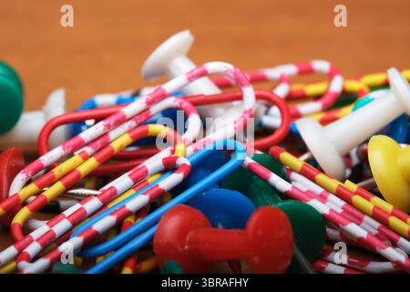 Verschiedene Büroklammern und Druckstifte auf einer strukturierten Oberfläche verstreut. Stockfoto