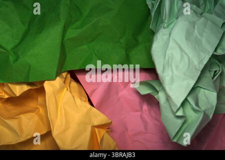 Schichten zerknitterten Papiers in Grün, Gelb und Rosa verleihen dem Papier einen lebendigen Touch. Stockfoto