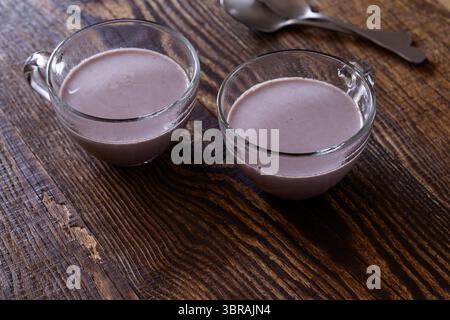 Süße heiße Schokolade in Glasbecher auf hölzernem Hintergrund Stockfoto