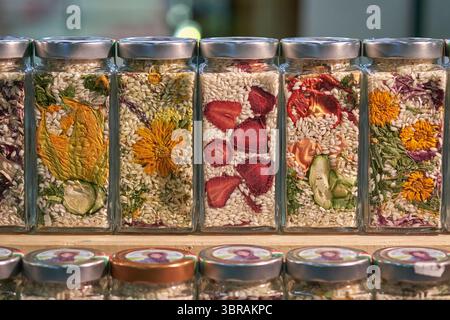 Glasgläser gefüllt mit getrocknetem Gemüse, Obst, Blumen und Reis. Eine lebendige und künstlerische Präsentation natürlicher Zutaten für Gourmet Stockfoto
