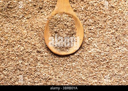 Weizenkleie auf Holzlöffel, Nahaufnahme. Detaillierte Textur verschiedener GetreideInstant-Kleie-Produkte. Gesunde Ernährung. Stockfoto