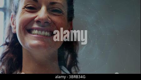 Lächelnde mittelerwachsene Frau in Kragenhemd im Studio, mit Zähnen und Vertiefungen mit Netzüberzug Stockfoto