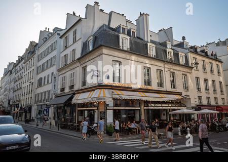 Eine klassische Pariser Brasserie an einer Straßenecke mit einladendem Sitzbereich im Freien, die traditionelle Architektur und das pulsierende Straßenleben bietet. Stockfoto