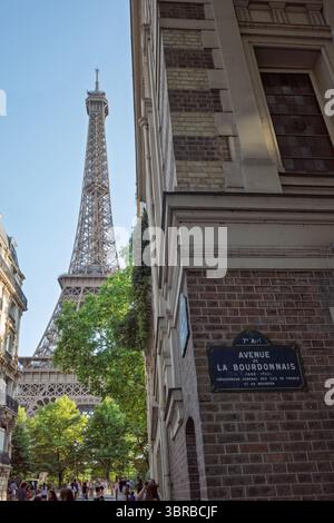 Ein eindrucksvoller Blick auf den Eiffelturm zwischen Pariser Gebäuden mit dem Straßenschild Avenue de la Bourdonnais. Stockfoto