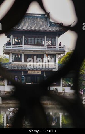 Ein ruhiger Blick auf traditionelle Architektur, eingerahmt von einem dekorativen Element mit Blick auf ein ruhiges Gewässer in einer wunderschönen Gartenanlage Stockfoto