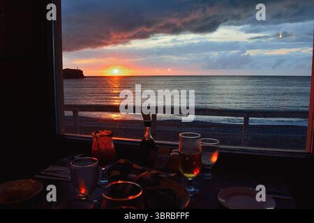 Abendessen bei Sonnenuntergang mit Meerblick durch das Fenster des Restaurants, Neufundland, Kanada Stockfoto