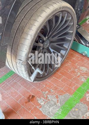 Reifenpannen in einer Garage mit Dichtmittel zur Reparatur einer Reifenpanne. Ein Autorad wird auf einem Wagenheber angehoben, während sich in der Nähe eine Sprühdose für Dichtmittel befindet Stockfoto