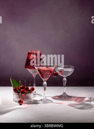 Erfrischende Kirschcocktails in elegantem Geschirr, begleitet von frischen Kirschen, sorgen für eine lebendige und raffinierte Getränkepräsentation Stockfoto