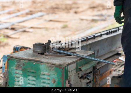 Ein Arbeiter verwendet auf der Baustelle eine Bewehrungsbiegemaschine. Stockfoto