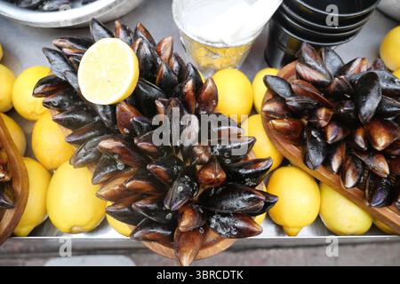 Frische Muscheln serviert mit Zitrone an einem Marktstand Stockfoto