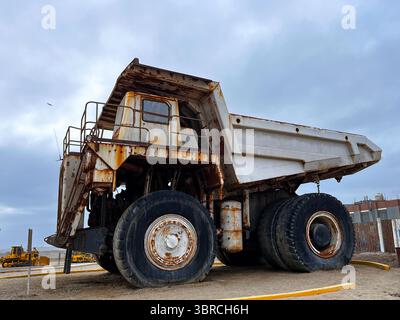 Großer, grauer, alter Müllwagen. Großer grüner, rostiger Bergbauwagen außer Betrieb, der an der Küste Perus in San Juan de Marcona ausgestellt wird. Bergbau Stockfoto